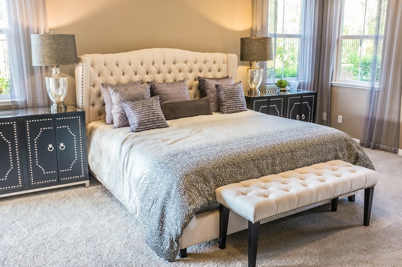 A bedroom with an upholstered bed and a bench