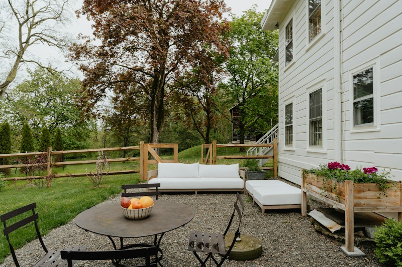 A gravel patio with outdoor seating beside a home