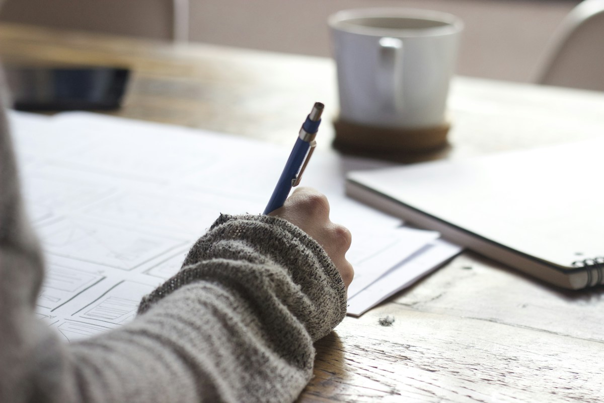A person reviewing paperwork and making notes at a desk