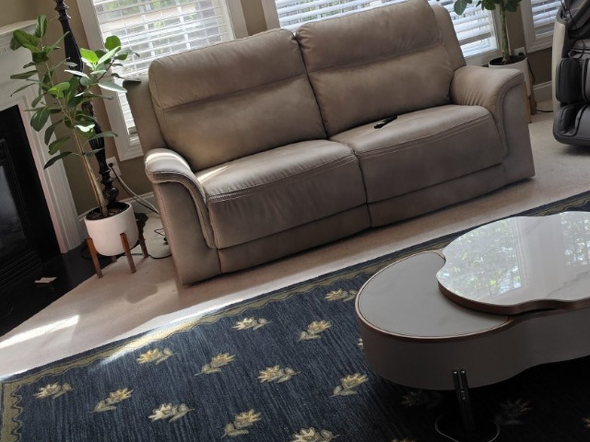 A lived-in family room with tall windows, a fireplace, and a well-used sofa and coffee table