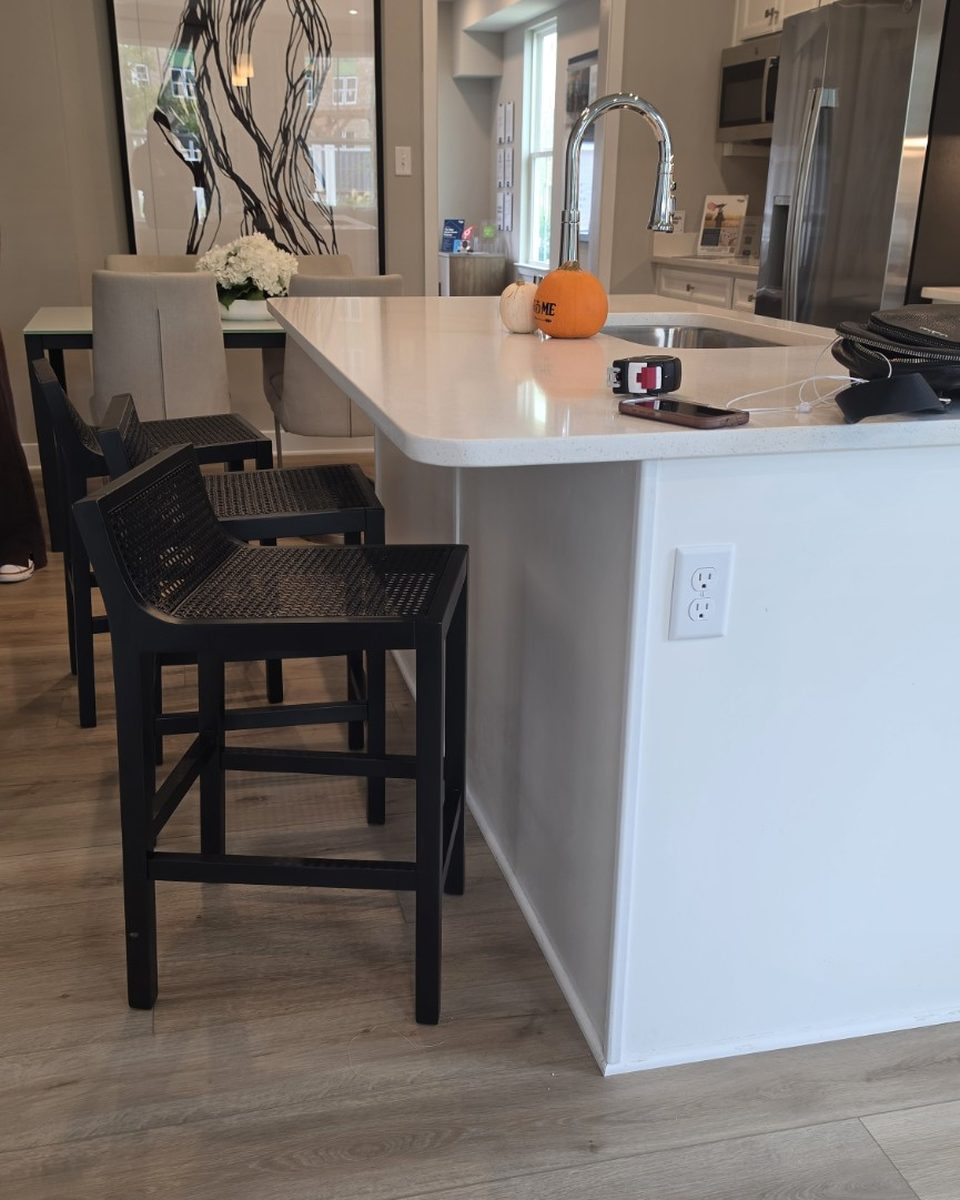 A clean kitchen with a white island and black counter stools