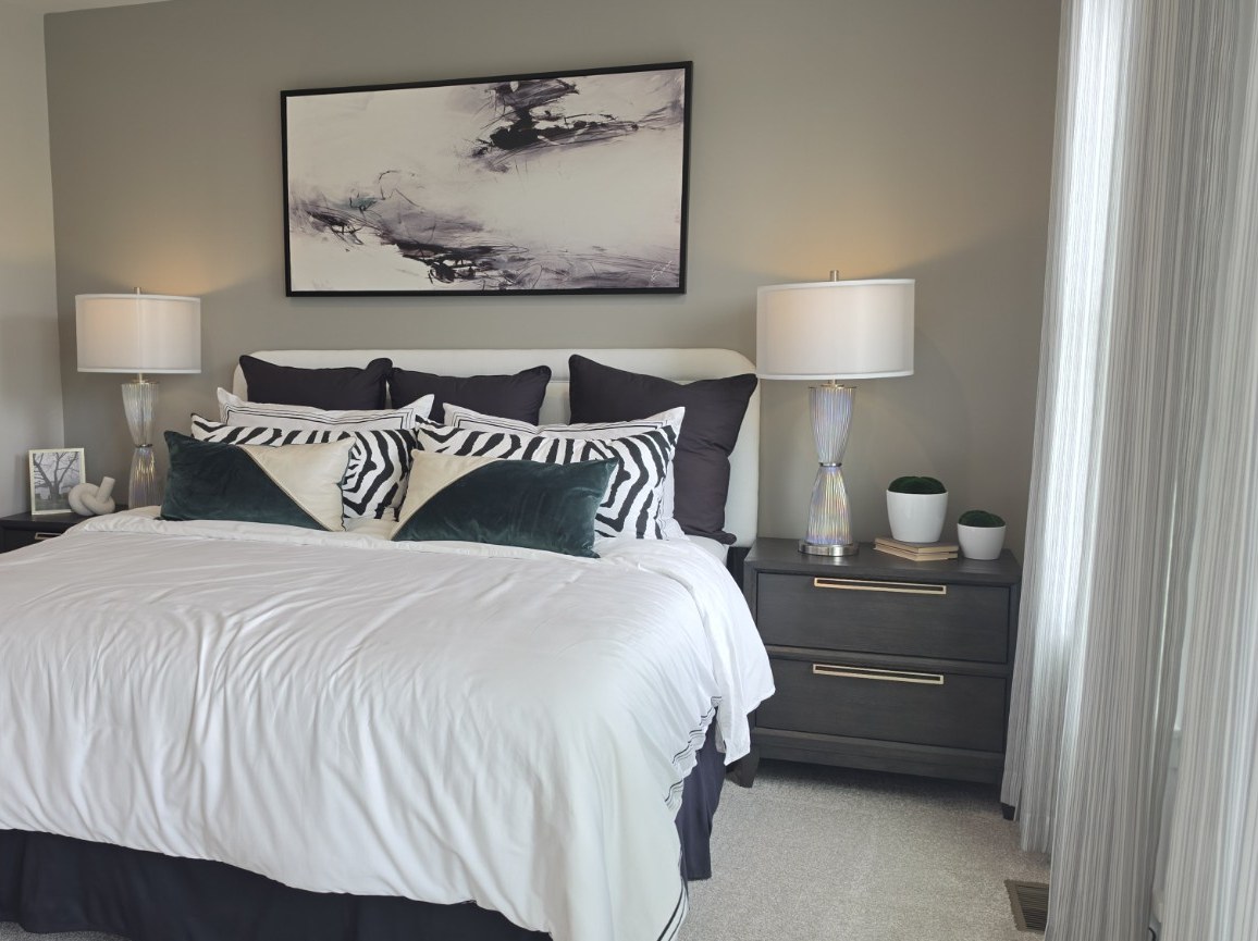 A made bed with layered pillows and matching lamps in a real bedroom